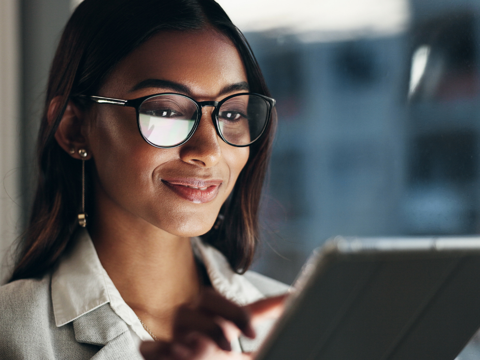 A student smiling as they review the contents of a tablet.