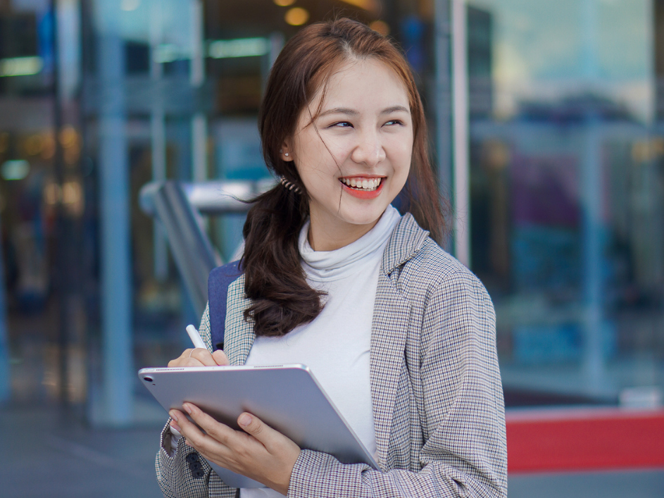A smiling student writing on a tablet.
