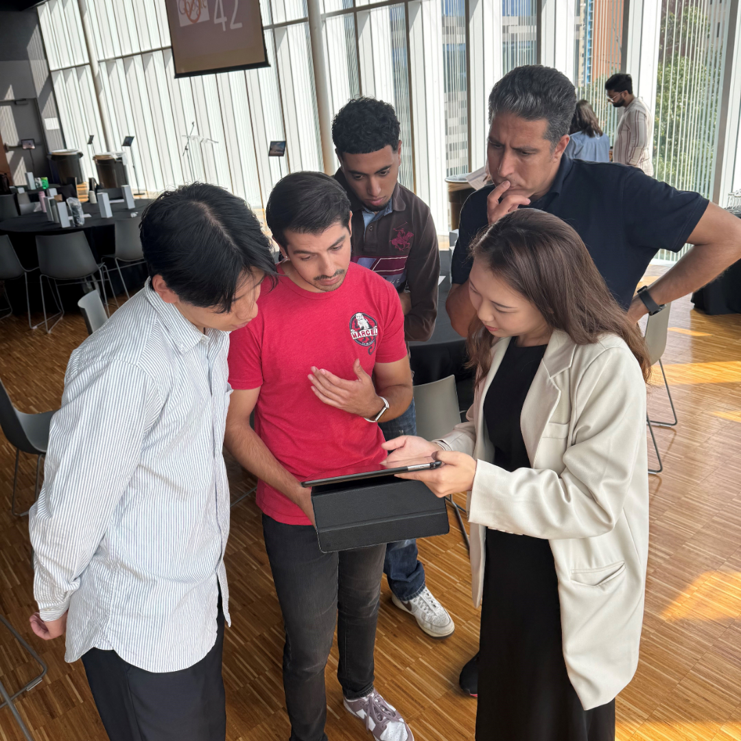 A student gesturing towards a tablet as she holds up her classmates to see.