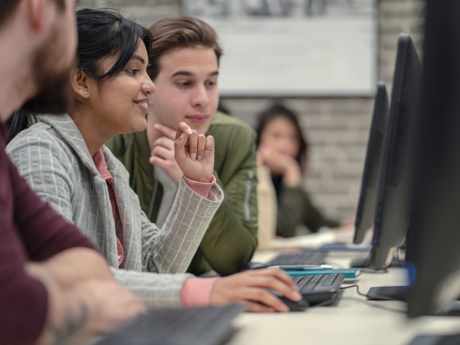 Three students look at a computer screen.